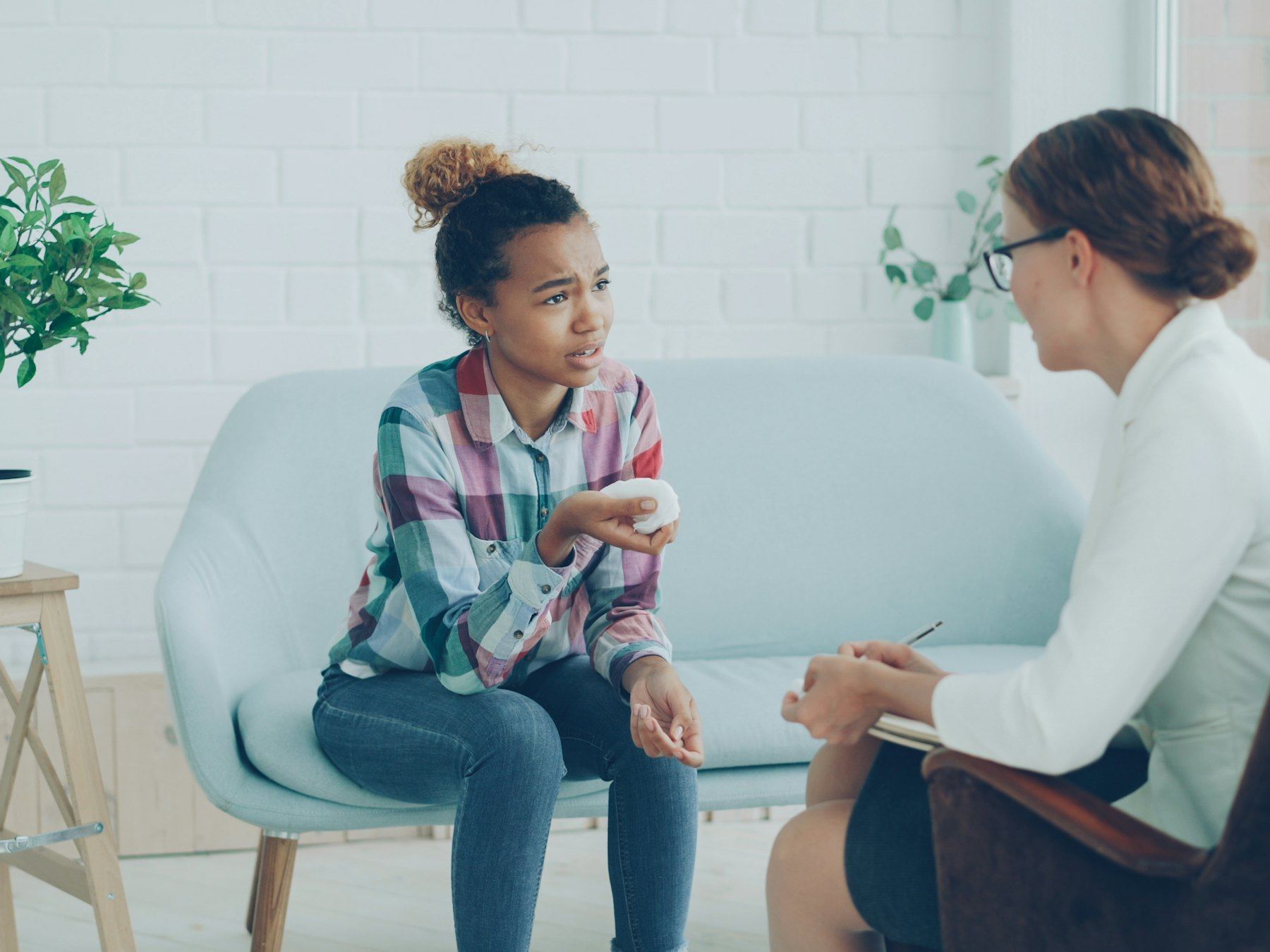 A therapist talking with a young girl on a couch